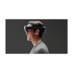 Side view of a man wearing a mixed reality headset with a glossy visor against a dark background.