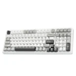 White computer keyboard with gray keys and a numeric keypad on a white surface, showing a retro-style layout on the keys.