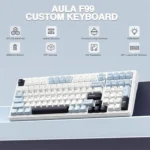 Aula f99 custom keyboard on a pale desk, highlighting features: bt5. 0/2. 4g wireless, gasket structure, pre-lubed linear switches, rgb backlight, 8000mah battery, pbt keycaps, hot-swappable, 96% layout with numpad.